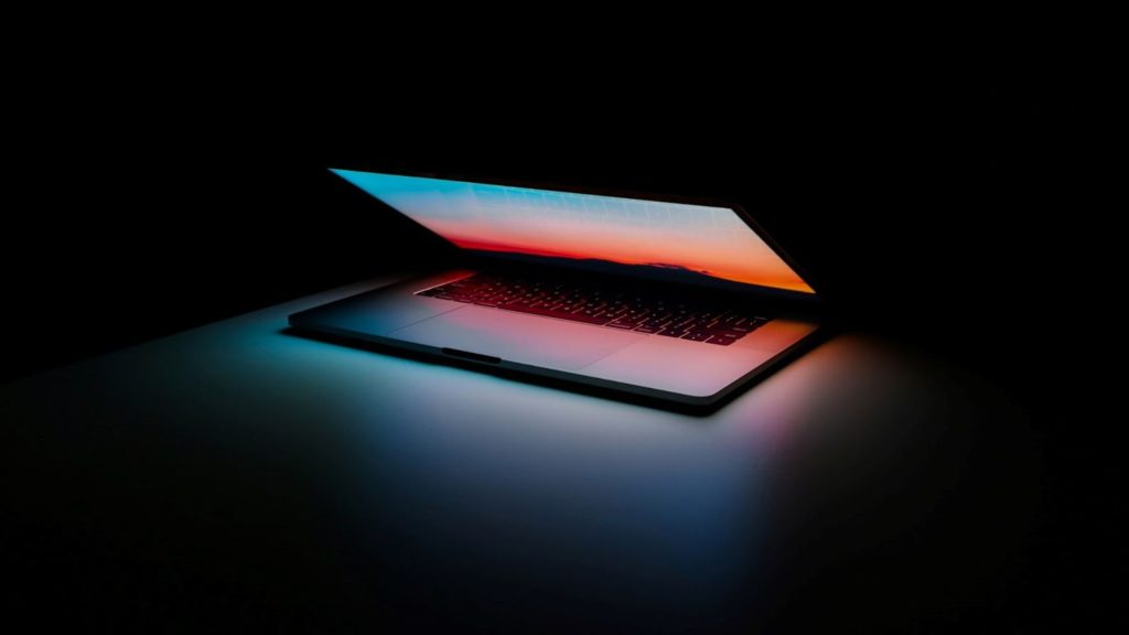 Imagen de una computadora portátil que brilla intensamente en un cuarto oscuro.