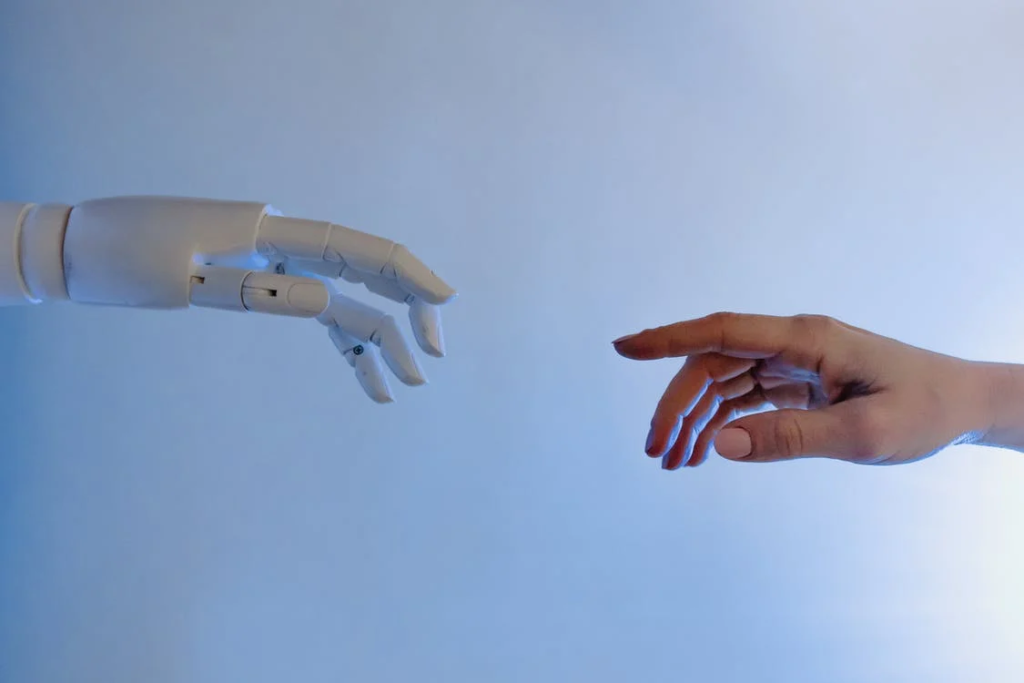 Imagen que muestra una mano robótica y una mano humana acercándose la una a la otra.