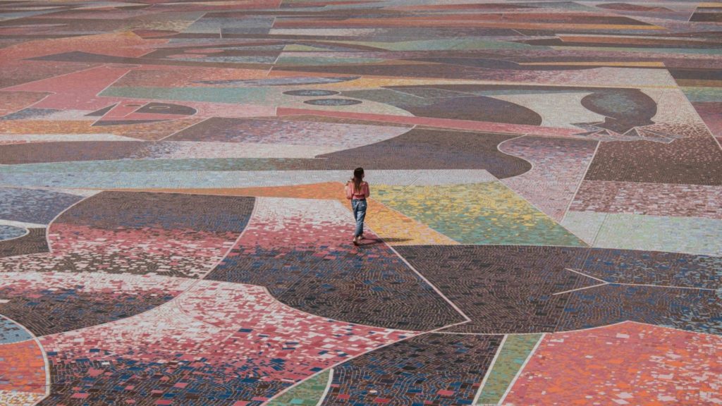Imagen de una mujer caminando sobre un gran diseño de mosaico.