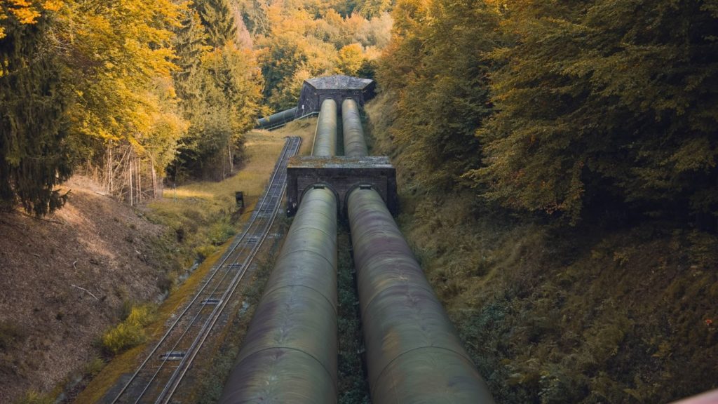 Imagen de viejos oleoductos junto a una vía de tren.