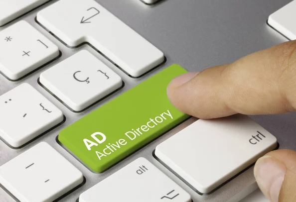 Una imagen gráfica de AD Active Directory escrita en una tecla verde de un teclado metálico.  con un dedo presionando la tecla.