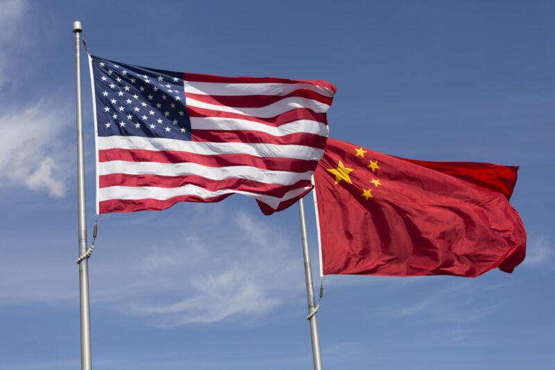 Las banderas de Estados Unidos y China ondeando en astas en un día ventoso.