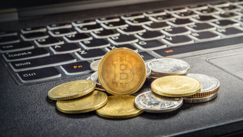 Una pila de monedas con el logotipo de bitcoin se encuentra sobre el teclado de una computadora portátil.