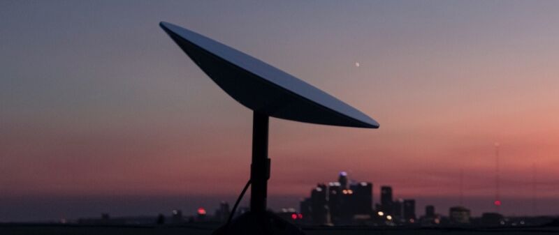Una terminal de usuario SpaceX Starlink, también conocida como antena parabólica, vista contra el horizonte de una ciudad.