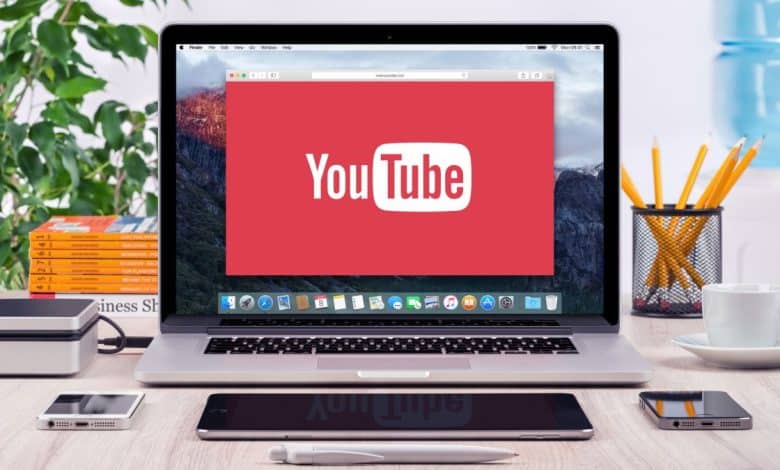 MacBook Pro open on a desk with YouTube logo on the screen
