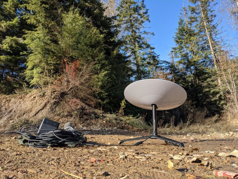 Una antena parabólica SpaceX Starlink colocada en el suelo en un claro del bosque.