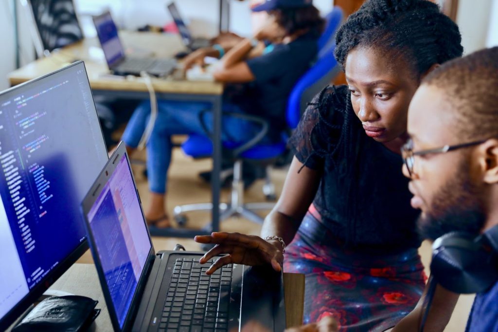 En Lagos, Nigeria, dos personas revisan imágenes de código en sus computadoras portátiles.