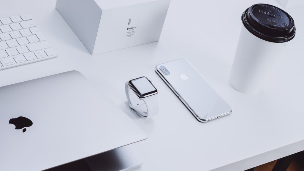 Productos de Apple, incluidos MacBook, Apple Watch y iPhone en una mesa blanca.