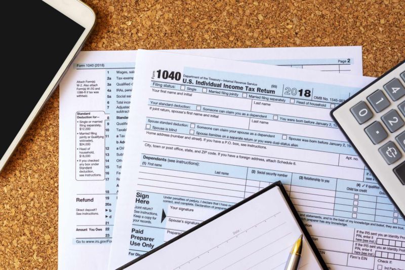 Un documento de declaración del impuesto sobre la renta de las personas físicas de EE. UU. sobre una mesa junto a una calculadora, un cuaderno, un bolígrafo y un iPad.