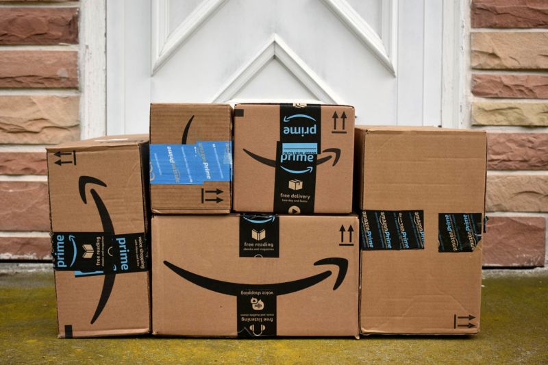 Un montón de cajas de Amazon frente a la puerta de una casa.