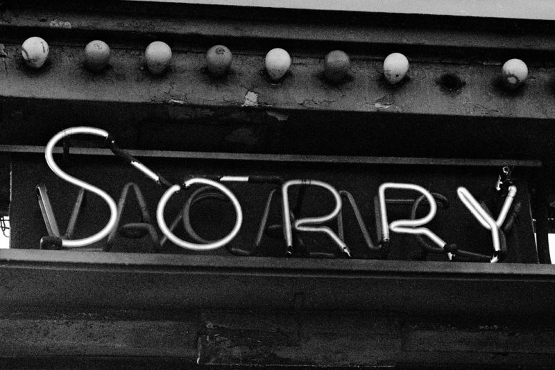 Fotografía en blanco y negro de un letrero de neón que dice LO SIENTO.